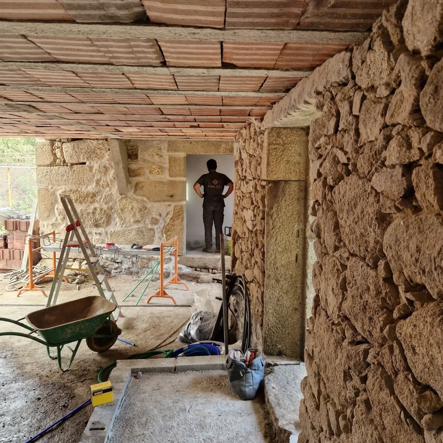 Interior de um edifício em pedra em reabilitação, com tubagem elétrica a descer pela parede
