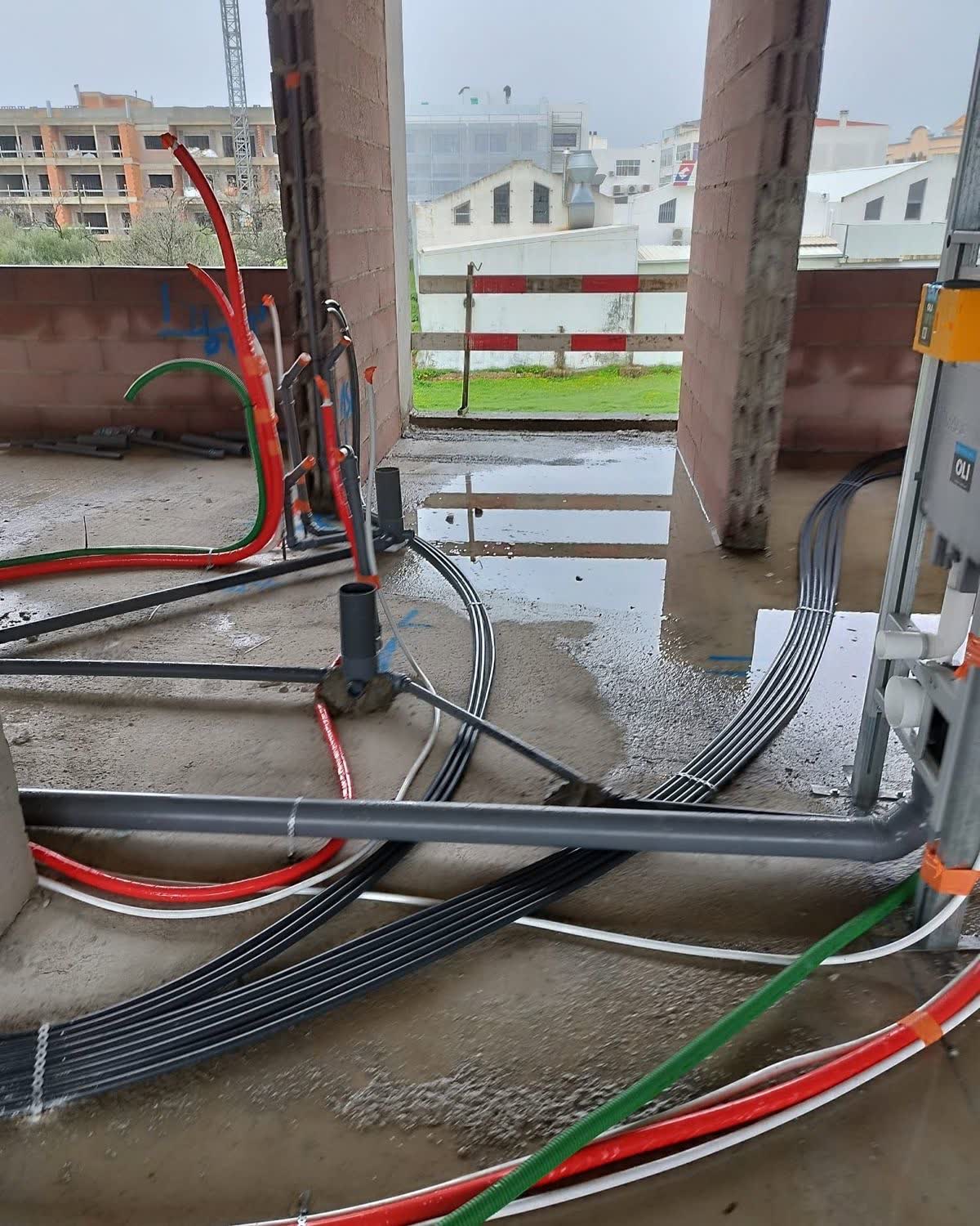 Tubagens elétricas e de águas num piso de edifício em construção, junto a pilares